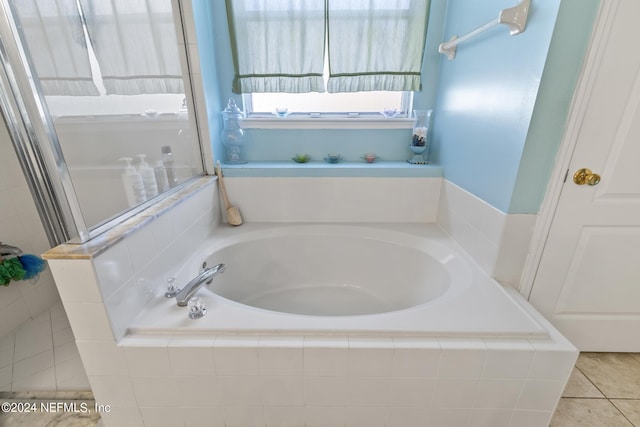 bathroom featuring a relaxing tiled tub and tile patterned flooring