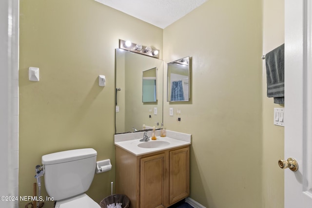 bathroom featuring vanity, a textured ceiling, and toilet