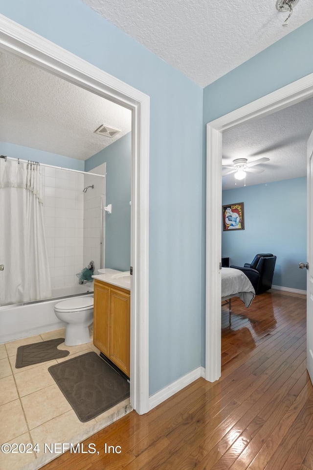 full bathroom featuring hardwood / wood-style flooring, ceiling fan, toilet, shower / bath combo, and a textured ceiling