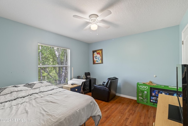 bedroom with wood-type flooring, a textured ceiling, and ceiling fan