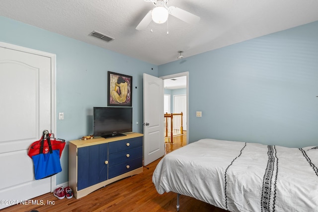 bedroom featuring dark wood-type flooring, a textured ceiling, and ceiling fan