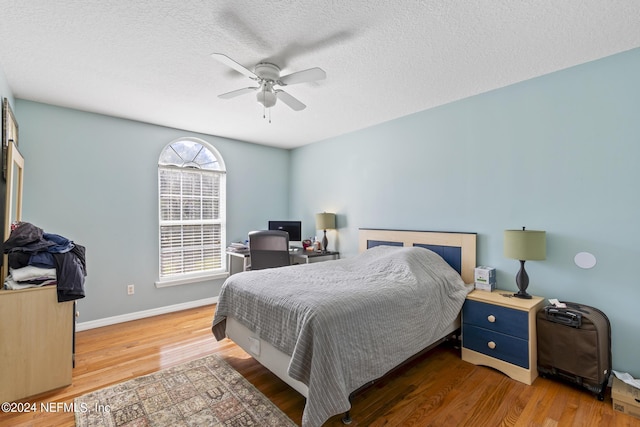 bedroom with ceiling fan, hardwood / wood-style floors, and a textured ceiling