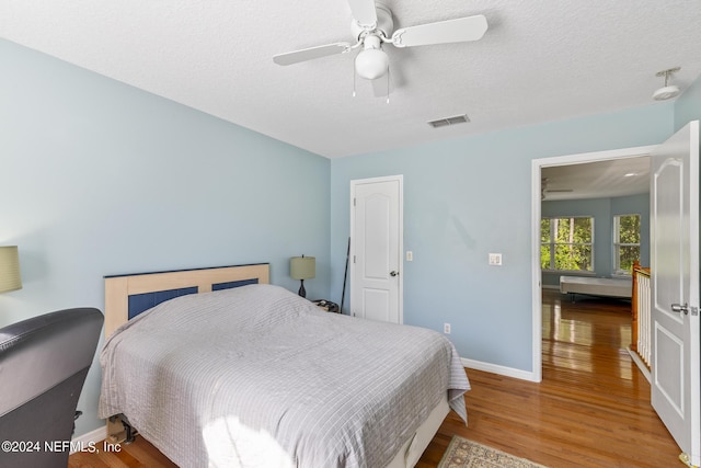 bedroom featuring a textured ceiling, wood-type flooring, and ceiling fan