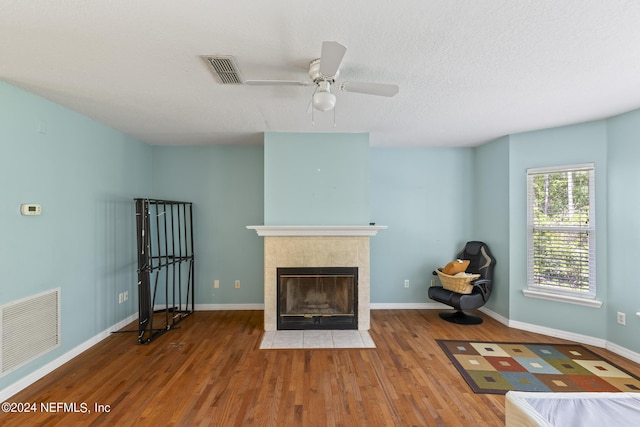 unfurnished living room featuring hardwood / wood-style flooring, a fireplace, a textured ceiling, and ceiling fan