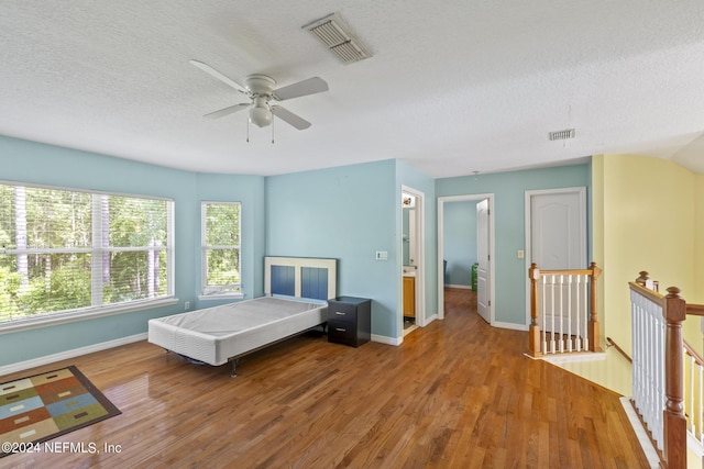 bedroom with wood-type flooring, a textured ceiling, and ceiling fan