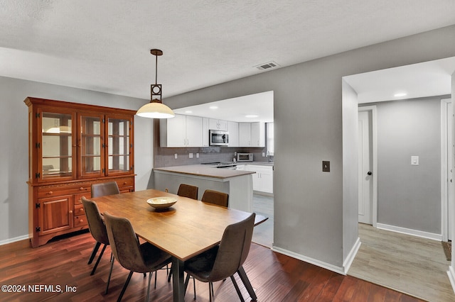 dining space featuring a textured ceiling and wood-type flooring