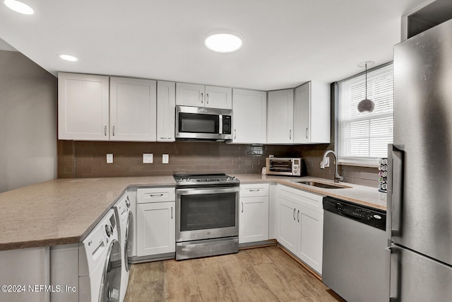 kitchen featuring decorative backsplash, light hardwood / wood-style flooring, hanging light fixtures, sink, and stainless steel appliances