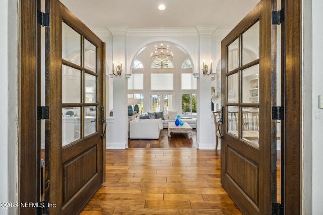 interior space featuring wood-type flooring, ornamental molding, and an inviting chandelier