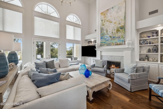 living room featuring a premium fireplace, plenty of natural light, dark hardwood / wood-style floors, and built in features