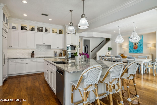 kitchen with sink, white cabinetry, an island with sink, pendant lighting, and light stone countertops