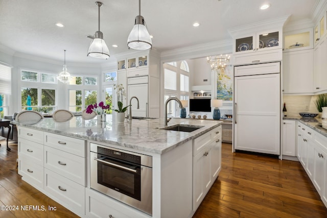 kitchen featuring a kitchen island with sink, sink, pendant lighting, and white cabinetry