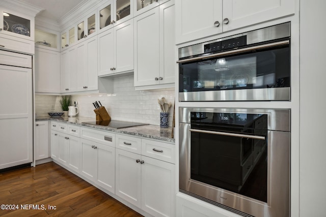 kitchen featuring black electric stovetop, white cabinets, light stone counters, and double oven