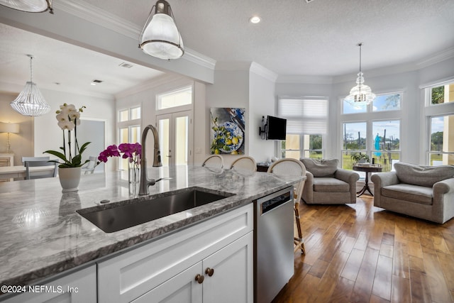 kitchen featuring pendant lighting, sink, white cabinetry, stainless steel dishwasher, and dark stone counters