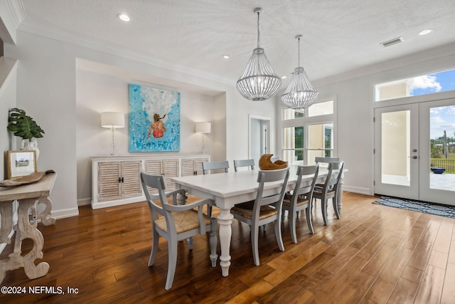 dining room featuring a chandelier, ornamental molding, dark wood-type flooring, a textured ceiling, and french doors