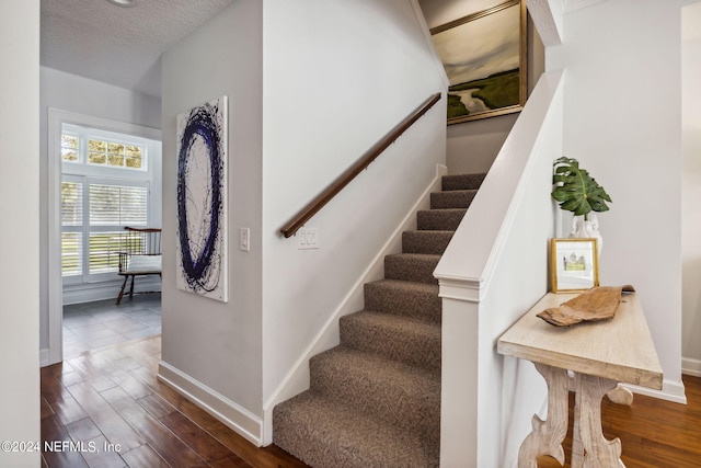 stairway featuring hardwood / wood-style floors and a textured ceiling