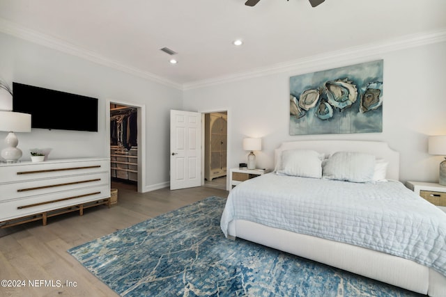 bedroom with crown molding, a spacious closet, a closet, and hardwood / wood-style flooring