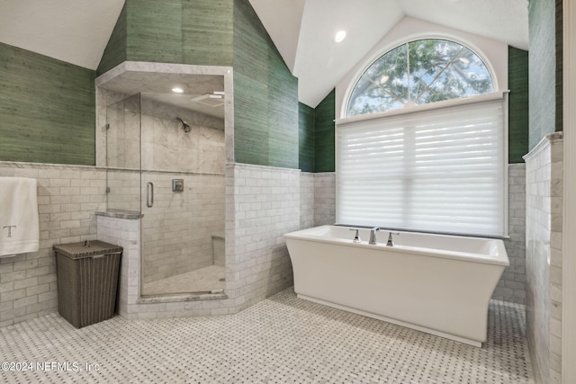 bathroom featuring independent shower and bath, lofted ceiling, tile walls, and tile patterned floors