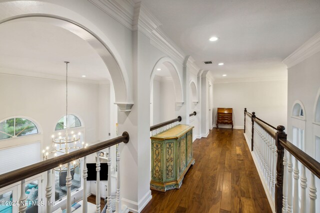 corridor with a notable chandelier, crown molding, and dark wood-type flooring