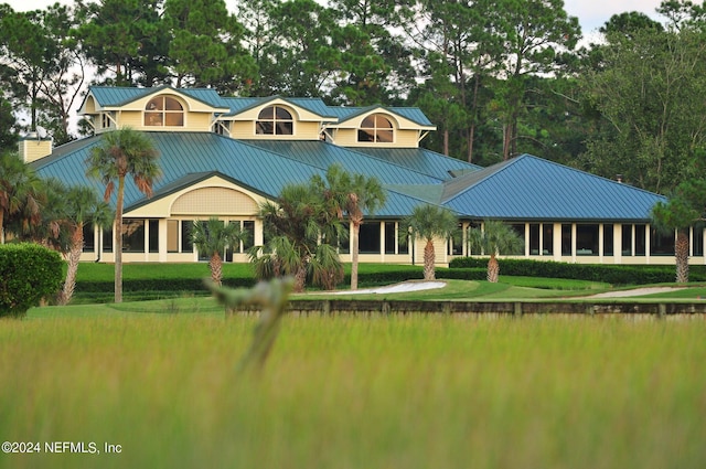 back of property with a lawn and a water view