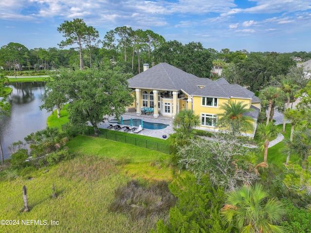 back of property with a patio area, a lawn, and a water view