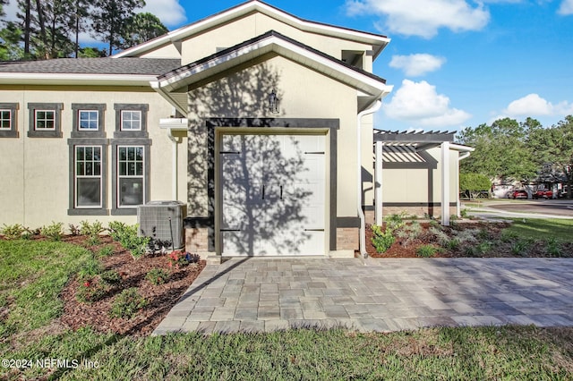 doorway to property with a pergola, a garage, and central AC unit