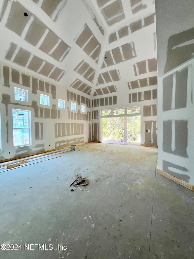 miscellaneous room featuring plenty of natural light, a high ceiling, and concrete flooring