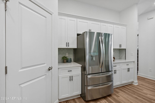 kitchen with light hardwood / wood-style floors, white cabinetry, stainless steel refrigerator with ice dispenser, and decorative backsplash