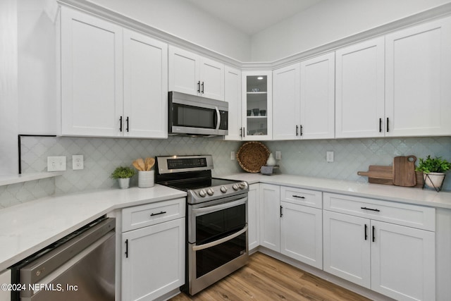 kitchen with decorative backsplash, light wood-type flooring, stainless steel appliances, and white cabinetry