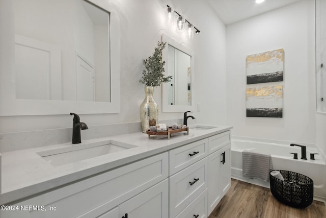 bathroom featuring wood-type flooring, double sink vanity, and a tub to relax in