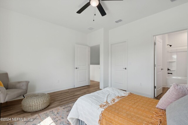 bedroom featuring hardwood / wood-style flooring, ensuite bathroom, and ceiling fan