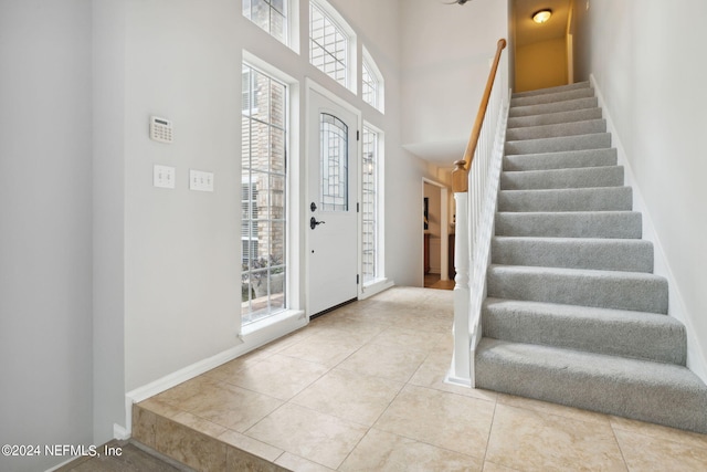 entryway featuring light tile patterned floors and a towering ceiling