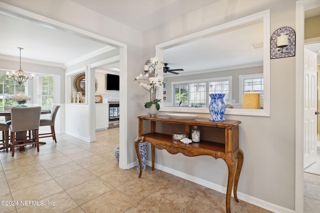 hall featuring plenty of natural light, an inviting chandelier, light tile patterned floors, and ornamental molding