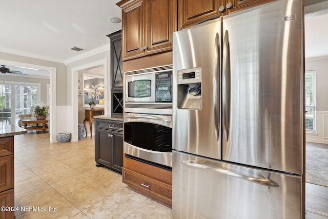 kitchen with ceiling fan, light stone countertops, stainless steel appliances, and ornamental molding