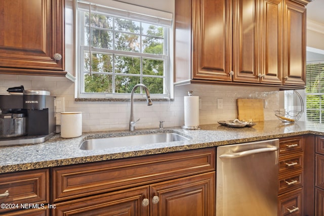 kitchen featuring decorative backsplash, dishwasher, light stone countertops, and sink