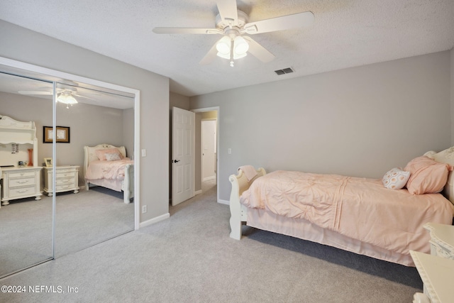 bedroom featuring light carpet, a textured ceiling, a closet, and ceiling fan