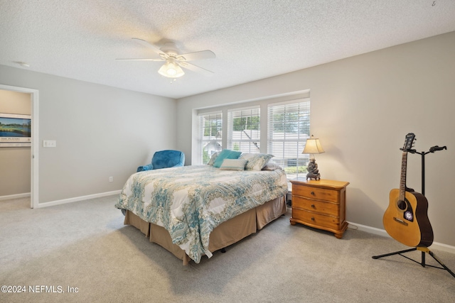 bedroom with ceiling fan, light colored carpet, and a textured ceiling