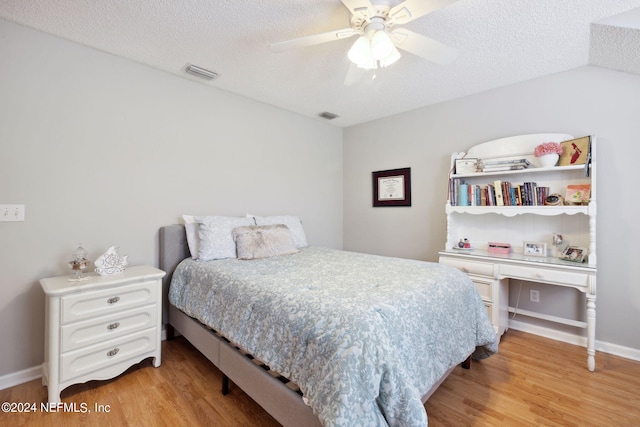 bedroom featuring ceiling fan, light hardwood / wood-style floors, and a textured ceiling