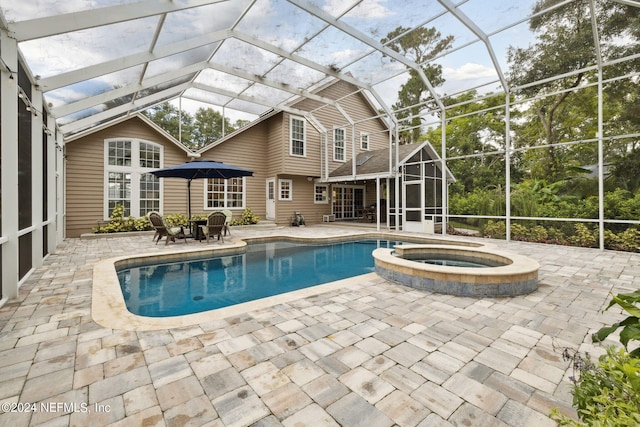 view of swimming pool with glass enclosure, an in ground hot tub, and a patio