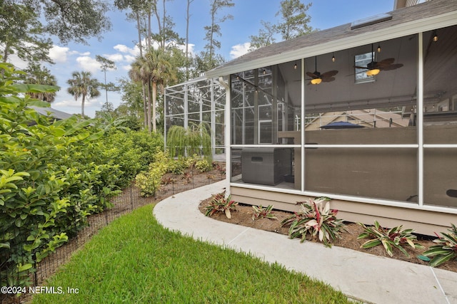 view of yard with ceiling fan and a lanai