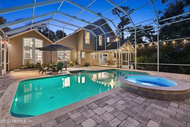 view of swimming pool featuring an in ground hot tub, a patio, and a lanai