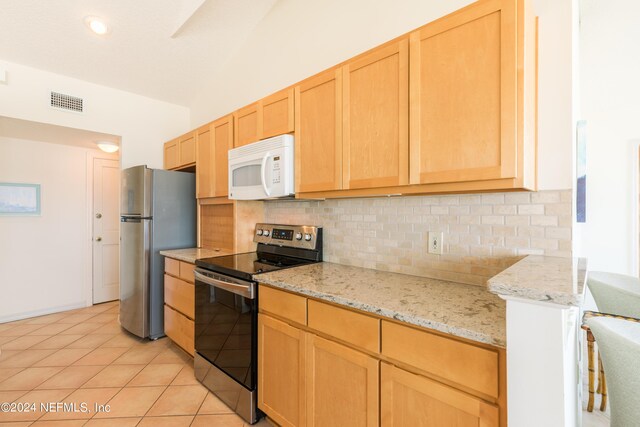 kitchen with light tile patterned flooring, appliances with stainless steel finishes, light brown cabinetry, backsplash, and light stone countertops