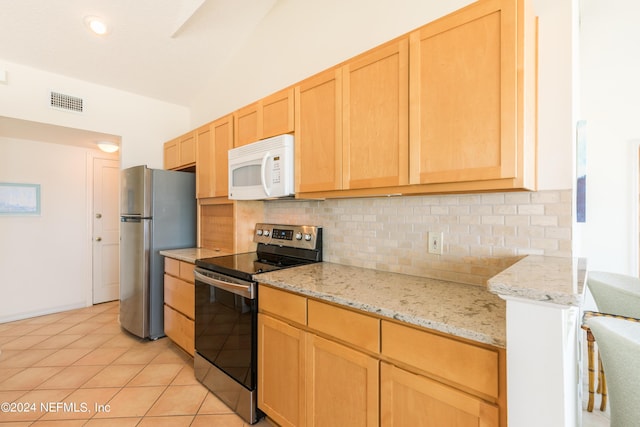 kitchen with light tile patterned floors, appliances with stainless steel finishes, light brown cabinets, and tasteful backsplash