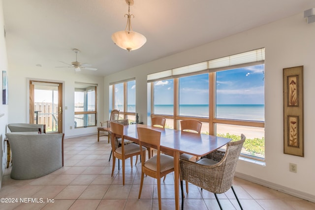 dining area with a ceiling fan, a water view, baseboards, and light tile patterned floors