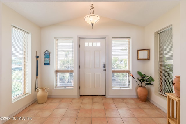 entryway with lofted ceiling, light tile patterned flooring, plenty of natural light, and baseboards