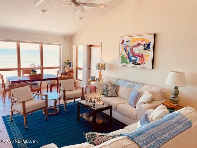 living room with ceiling fan, vaulted ceiling, and tile patterned floors