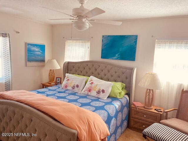 bedroom with ceiling fan and a textured ceiling