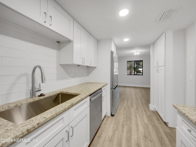 kitchen with sink, white cabinets, decorative backsplash, and appliances with stainless steel finishes