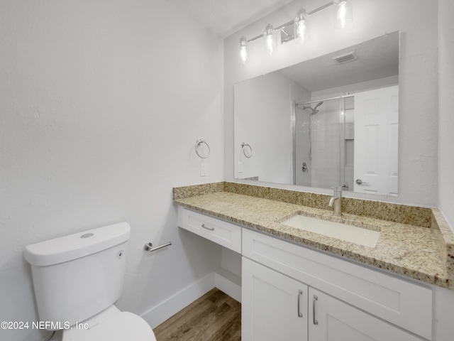 bathroom featuring wood-type flooring, toilet, a shower with door, and vanity