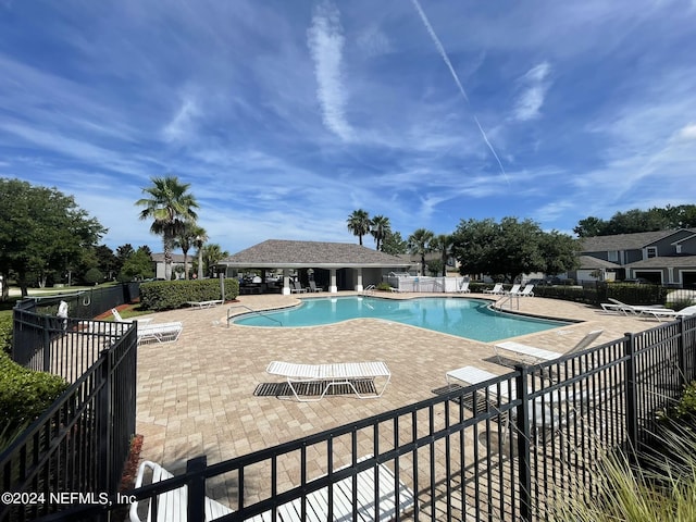 community pool featuring fence and a patio