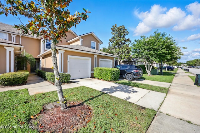 traditional-style house with stucco siding, concrete driveway, an attached garage, and a front yard
